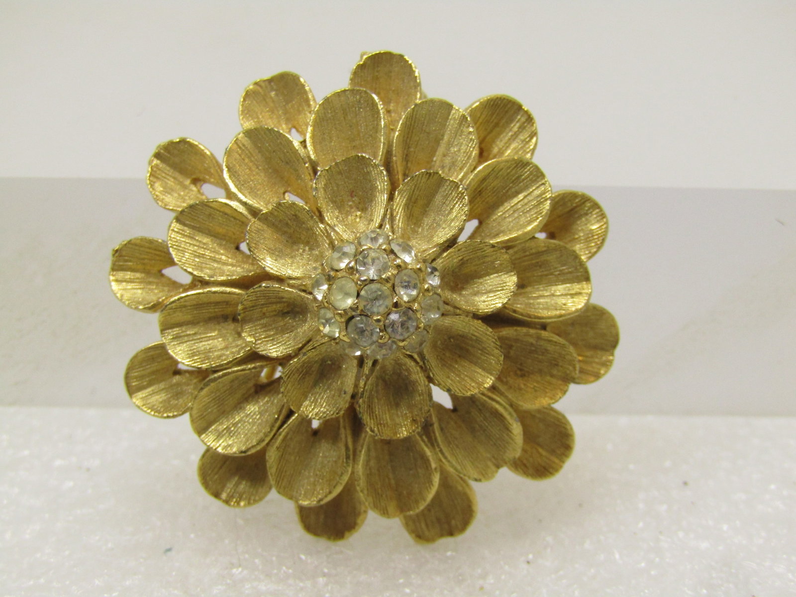Vintage Tiered Blossom Brooch, Rhinestop Center, 1970's: Vintage Tiered Blossom Brooch, Rhinestop Center, 1970's. Gold tone with a mum or dahlia look. It is appx. 1.5" wide with a textured look with rolled/curled petals in concentric circles in three tiers.