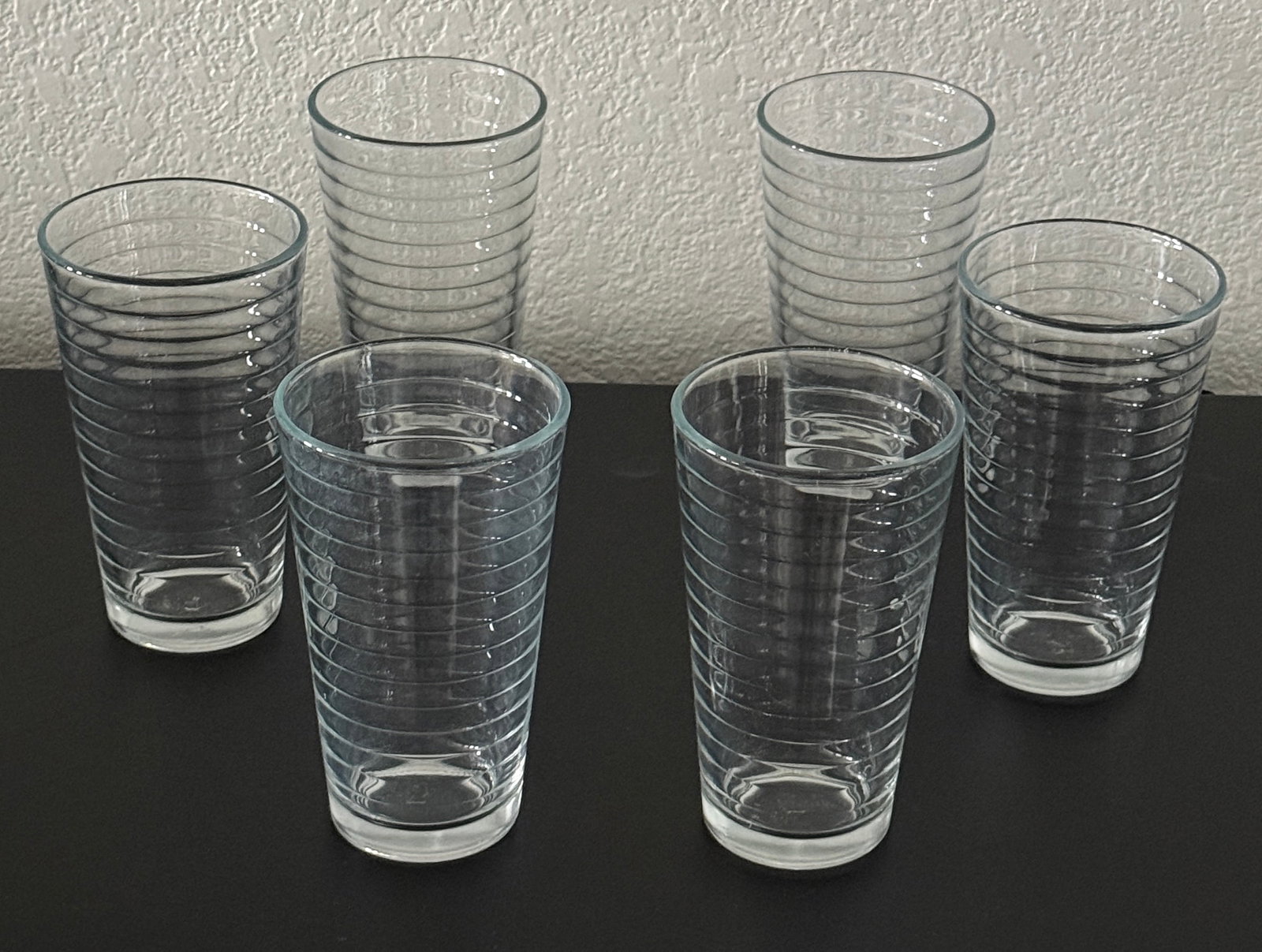 Set of Six Short Ribbed Glass Tumblers: A set of six clear glass tumblers, each featuring a ribbed design for an enhanced grip and decorative appeal. These versatile glasses are suitable for various beverages, from water to cocktails. The a