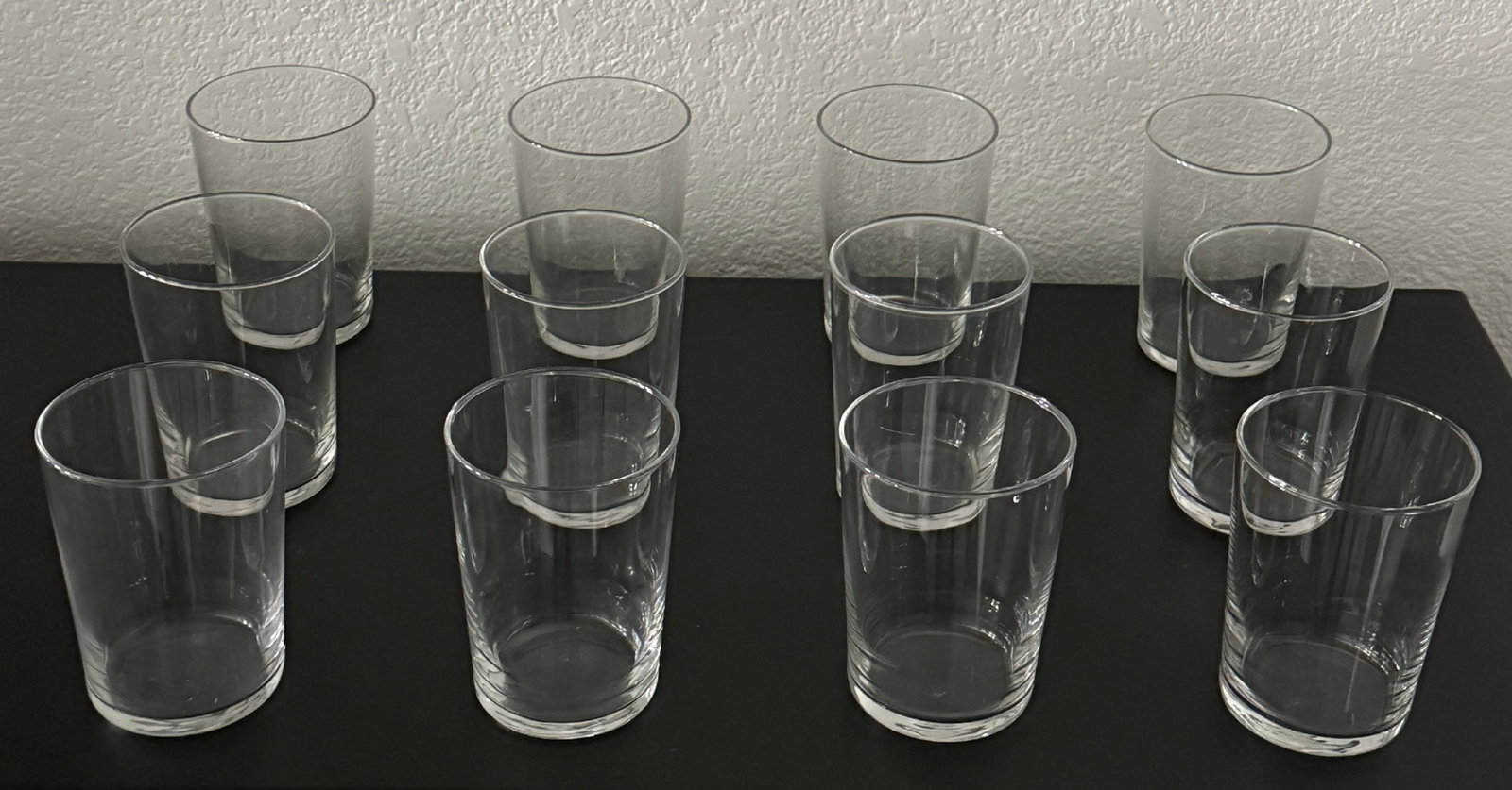 Set of 12 Clear Glass Tumblers: A set of twelve clear glass tumblers, likely dating from the mid to late 20th century. These classic, undecorated tumbler glasses are suitable for everyday use. The simple cylindrical design with a sl
