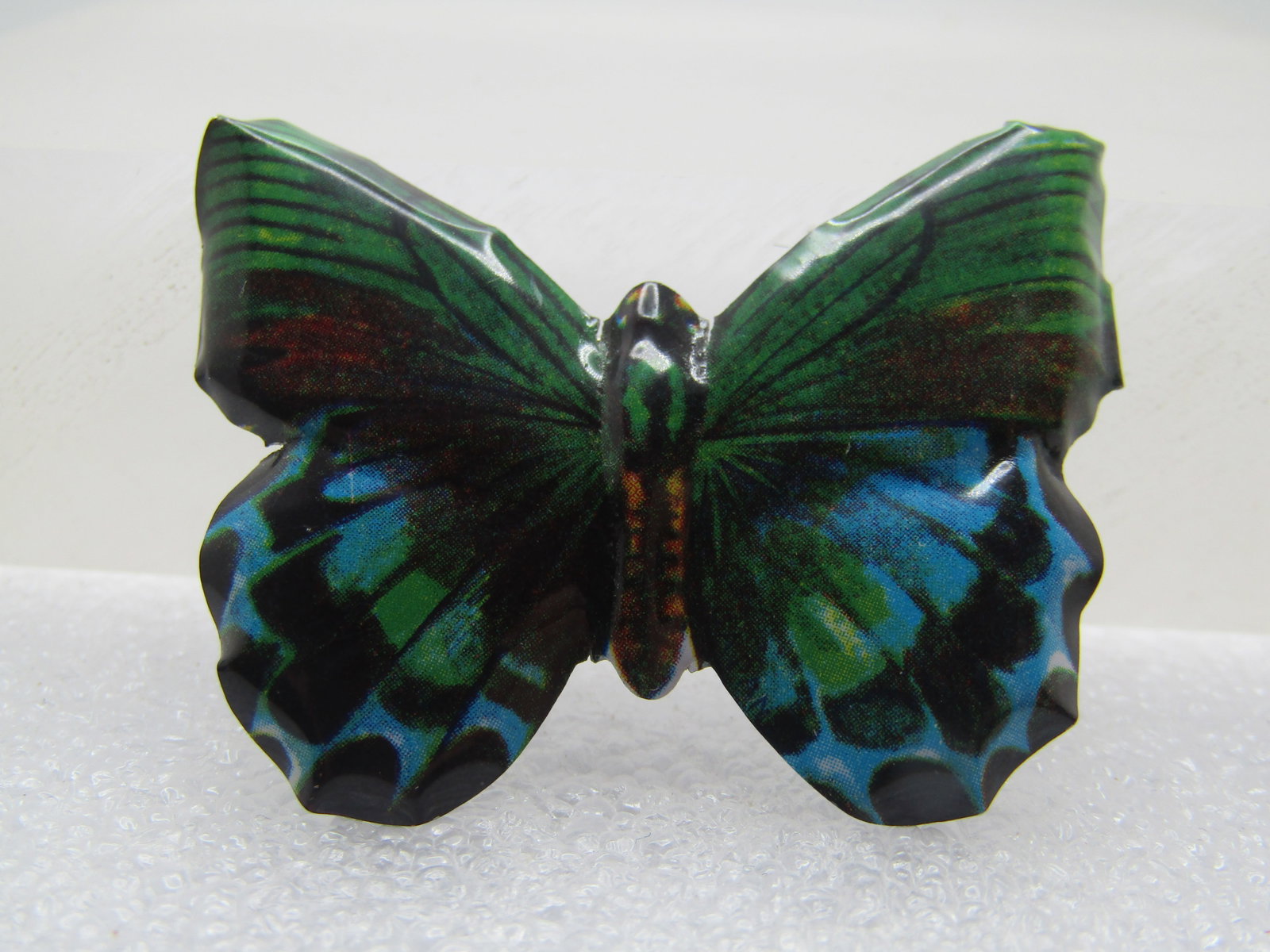 Vintage Enameled Litho Butterfly Brooch, 1950's-1960's: Vintage Enameled Litho Butterfly Brooch, 1950's-1960's. It is in green, red, black, teal, and blue. It is appx. 1.75" wide and 1.5" tall. Pinback hs a bent-metal clasp - much like a c-clasp. Very clea