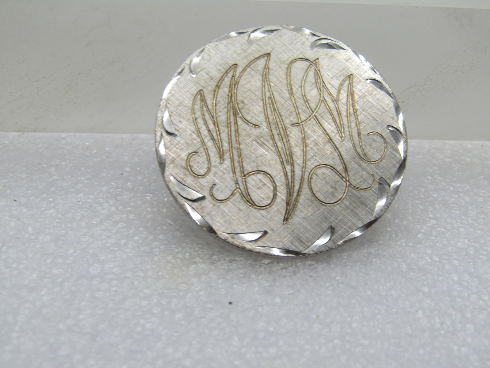 Vintage Sterling Monogrammed MVM Brooch, 1970's: Vintage Sterling Monogrammed MVM Brooch, 1970's. This is round and appx. 1.25" across with diamond-cut accents framing the brooch. Brushed background and Engraved MVM letter. It is marked on the back 