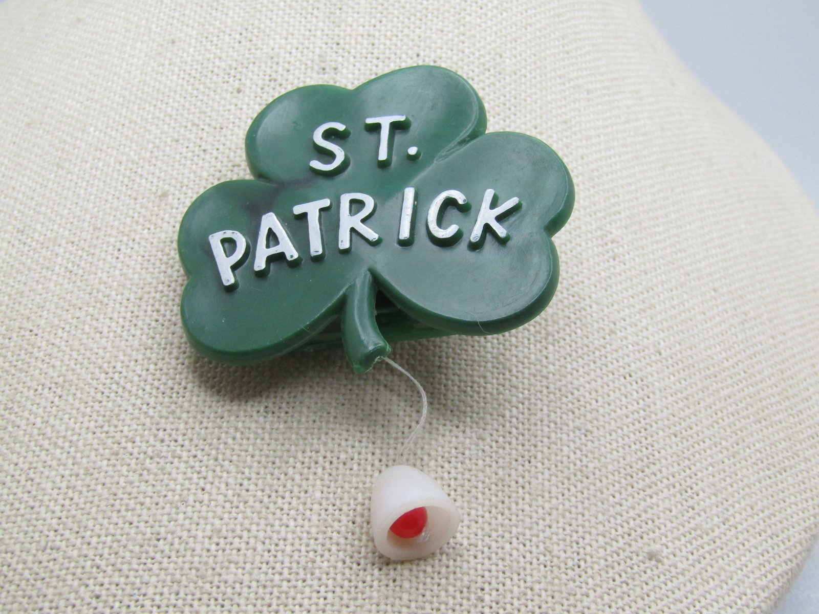 Vintage St. Patrick Clover Brooch, Pop Up Leprechaun, 1960's: Vintage St. Patrick Clover Brooch, Pop Up Leprechaun, 1960's. It has white raised St. Patrick lettering on the face, green plastic clover with a dangle whie and red pull down that causes a leprechaun