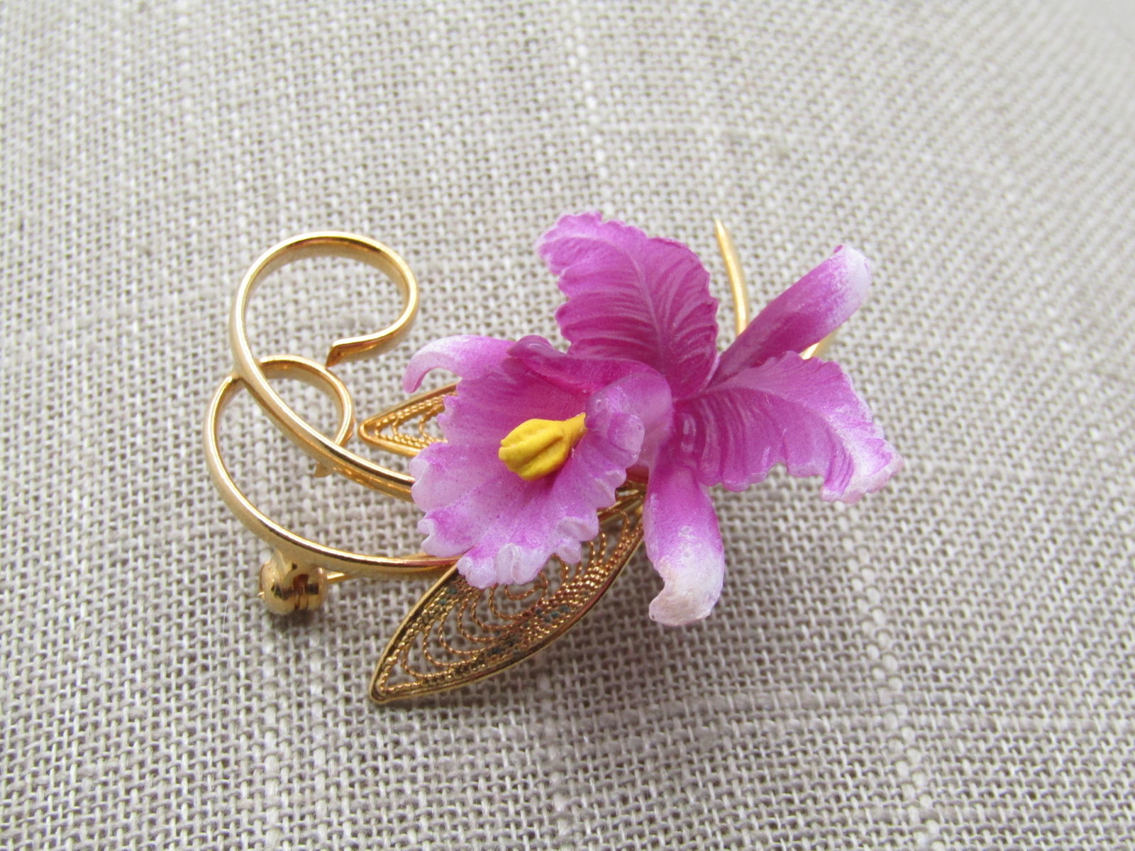 Vintage Orchid Stem Brooch, 1960's 2": Vintage Orchid Stem Brooch, 1960's 2" tall by 1.5" wide. Gold tone filigree leaves that sit under the orchid molded orchi with coiled/curled stems. Lockign clasp. Very clean and in very good