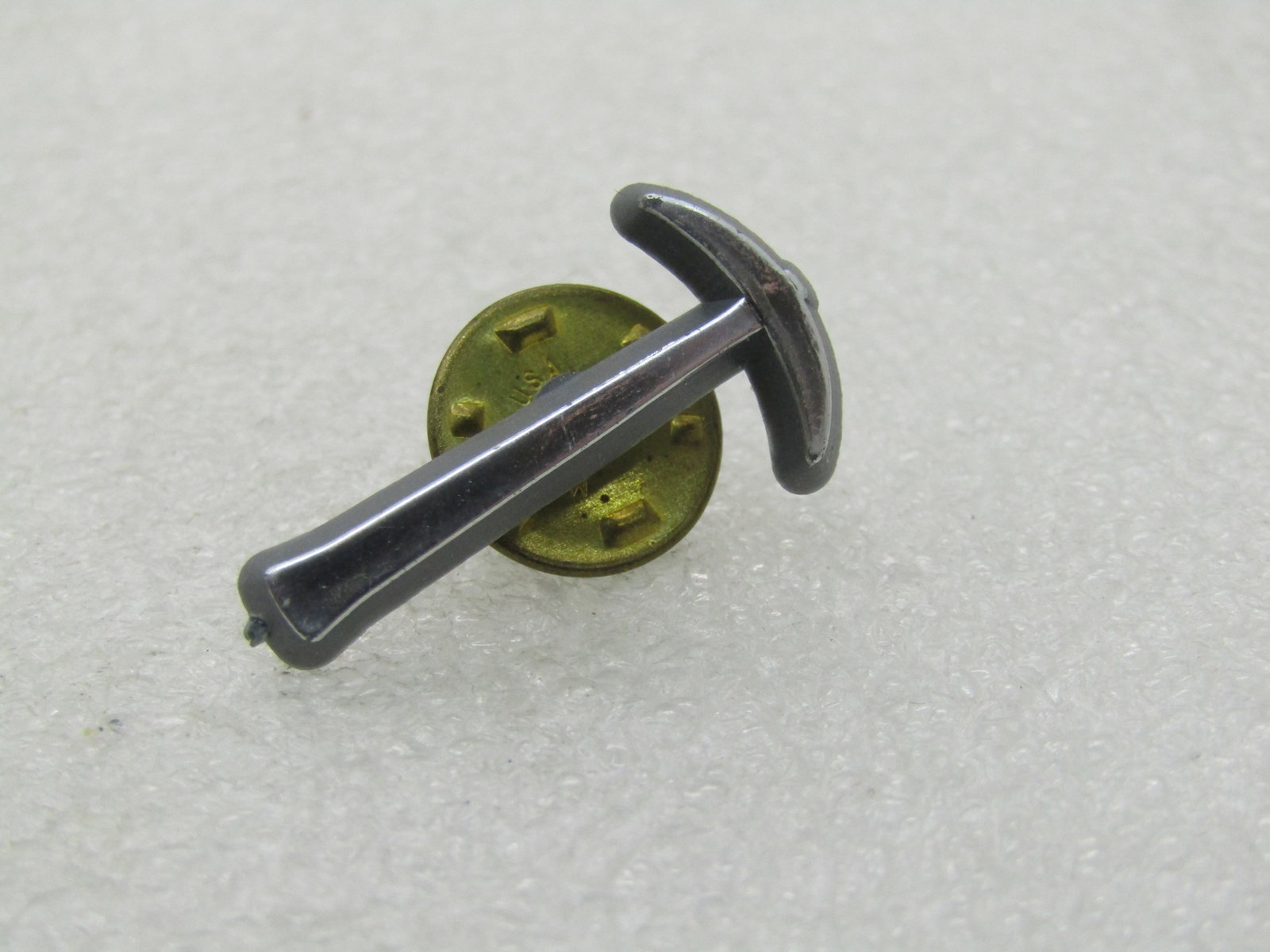 Vintage Silver Plastic Pickaxe Tie Tack: Vintage Silver Plastic Pickaxe Tie Tack 1" long and appx. 1/2" at the pickaxe. Very good condition. Not signed by the maker. Age is 1960's or slightly after. (INV. W. 13021.2 SS3636 LEB* LD 5/10/21). 