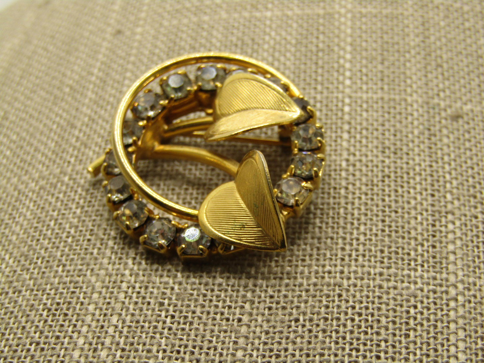 Vintage Clear Rhinestone Leaf Circle Brooch, 1960's: Vintage Clear Rhinestone Leaf Circle Brooch, 1960's, Gold tone with two hear-shaped textured leaves that have angled design and a double circle, one clear rhinestones and the other a round smaller rou