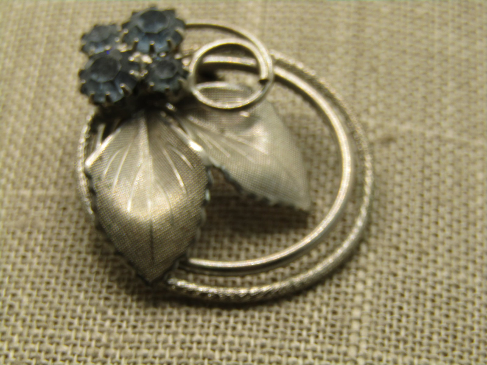 Vintage Circle Leaf Brooch with Blue Rhinestones, 1960's , 1.5": Vintage Circle Leaf Brooch with Blue Rhinestones, 1960's , 1.5" by 1.25". Double circle and two textured leafes with a coiled accent and 4 blue rhinestones. Some light wear, not signed by the maker.