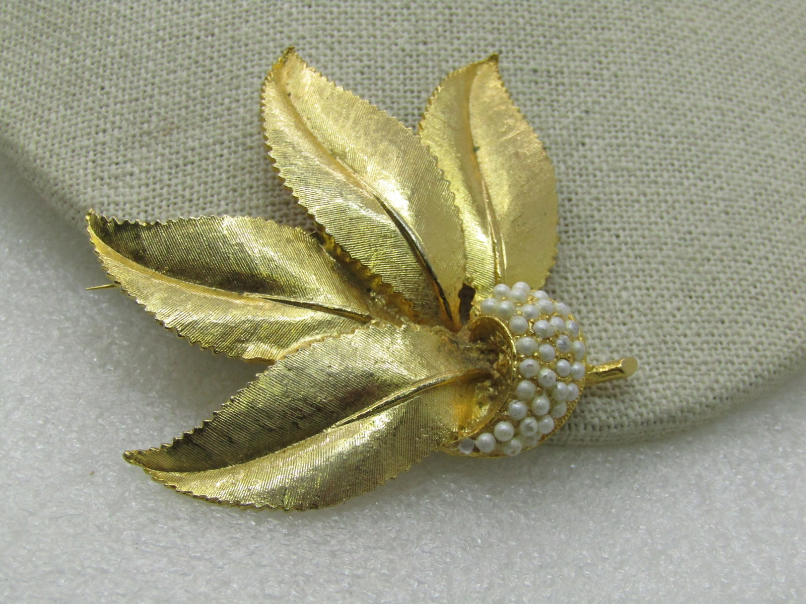 Vintage Gold Tone Leaf & Faux Pearl Brooch, 1960's: Vintage Gold Tone Leaf & Faux Pearl Brooch, 1960's, 3" by 2.75". Four textured blade leaves pointing upward with a curve of white faux pearl accents and a small shinyu stem at the bottom. Very good