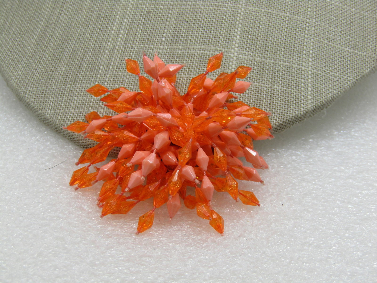 Vintage Orange Dangle Starburst Brooch, 2", 1960's: Vintage Orange Dangle Starburst Brooch, 2", 1960's. A mix of orange clear molded diamond-shaped beads on cord with a paler orange that is a solid color also molded on cord and dangle out from the