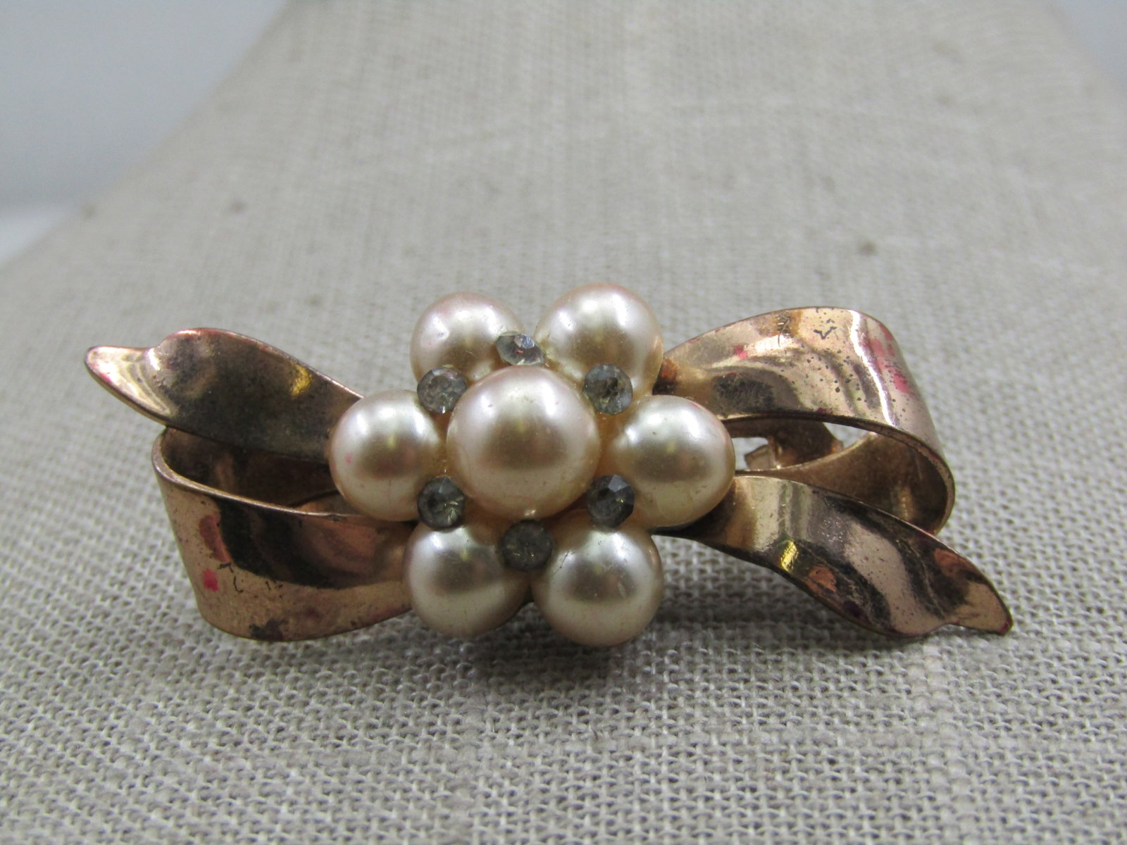 Vintage Faux Pearl & Rhinestone Bow Brooch, 1.75": Vintage Faux Pearl & Rhinestone Bow Brooch, 1.75" by nearly 1". Gold tone, 1950's-1960's with a center blossom of 6.5mm faux pearls that have a clear rhinestone between each pearl and at the base of