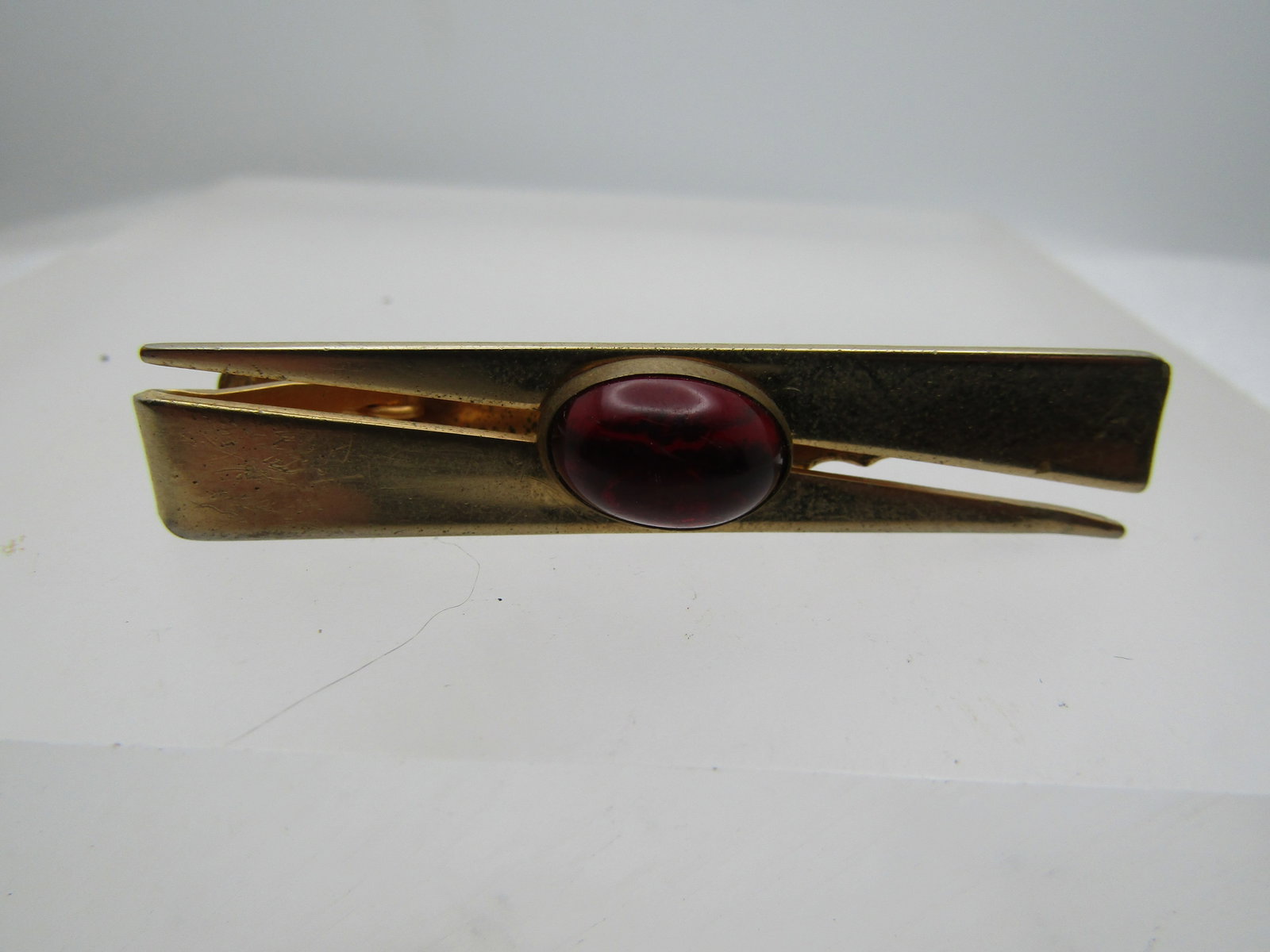 Vintage Red Stone Tie Clasp, Anson, 1940's-1950's, 2", Gold Tone: Vintage Red Stone Tie Clasp, Anson 1940's-1950's, 2", Gold Tone. This has a 12.5mm by 8.5mm bezel-set red domed stone on top that tests as acrylic/plastic. It has a split bypass design to the bar with