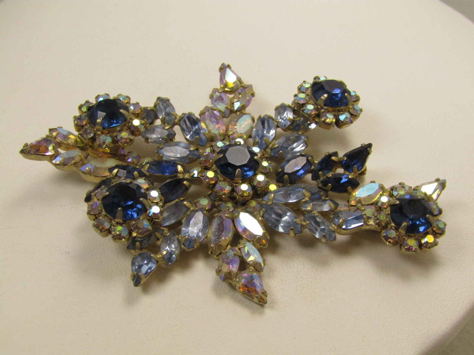 Vintage Blue & Clear Rhinestone Brooch, Aurora Borealis, 1940's-1950's.: Vintage Blue & Clear Rhinestone Brooch, Aurora Borealis, 1940's-1950's. This is gold tone with prong-set closed black settings to the stones. There are five blossom-like settings that have an appx.