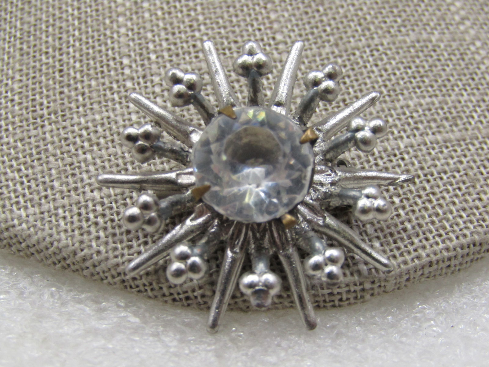 Vintage Silver Tone Rhinestone Starburst Brooch, 1940's-1950's: Vintage Silver Tone Rhinestone Starburst Brooch, 1940's-1950's. 1.25" across with a botton tier of pointed rays with the next tier slightly shorter and a beaded design and in the center is a clear 10.