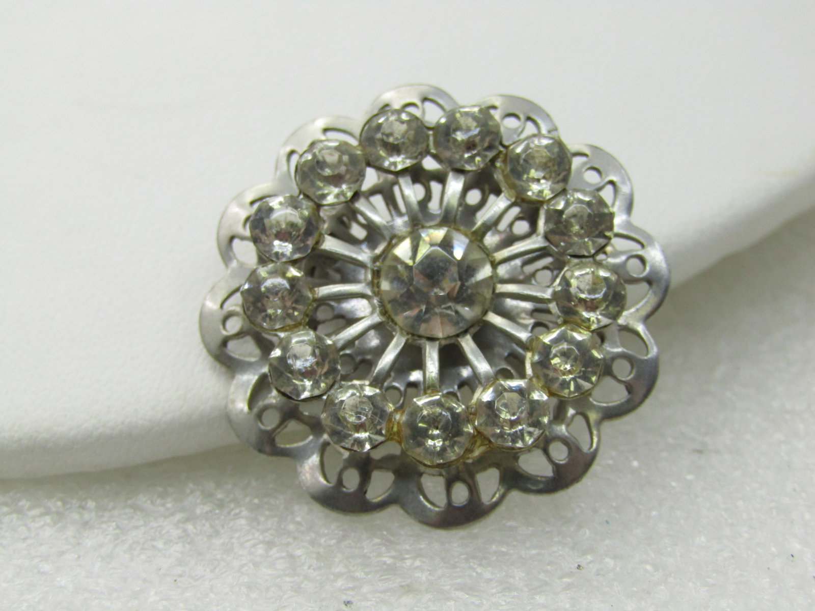 Vintage Rhinestone Round Blossom Brooch, Silver Tone, 1950's, 1.25": Vintage Rhinestione Round Blossom Brooch, Silver Tone, 1950's, 1.25" a halo of 4mm clear galss rhinetones on the upper level with a center 7mm stone that is slightly recessed and a filigree scalloped