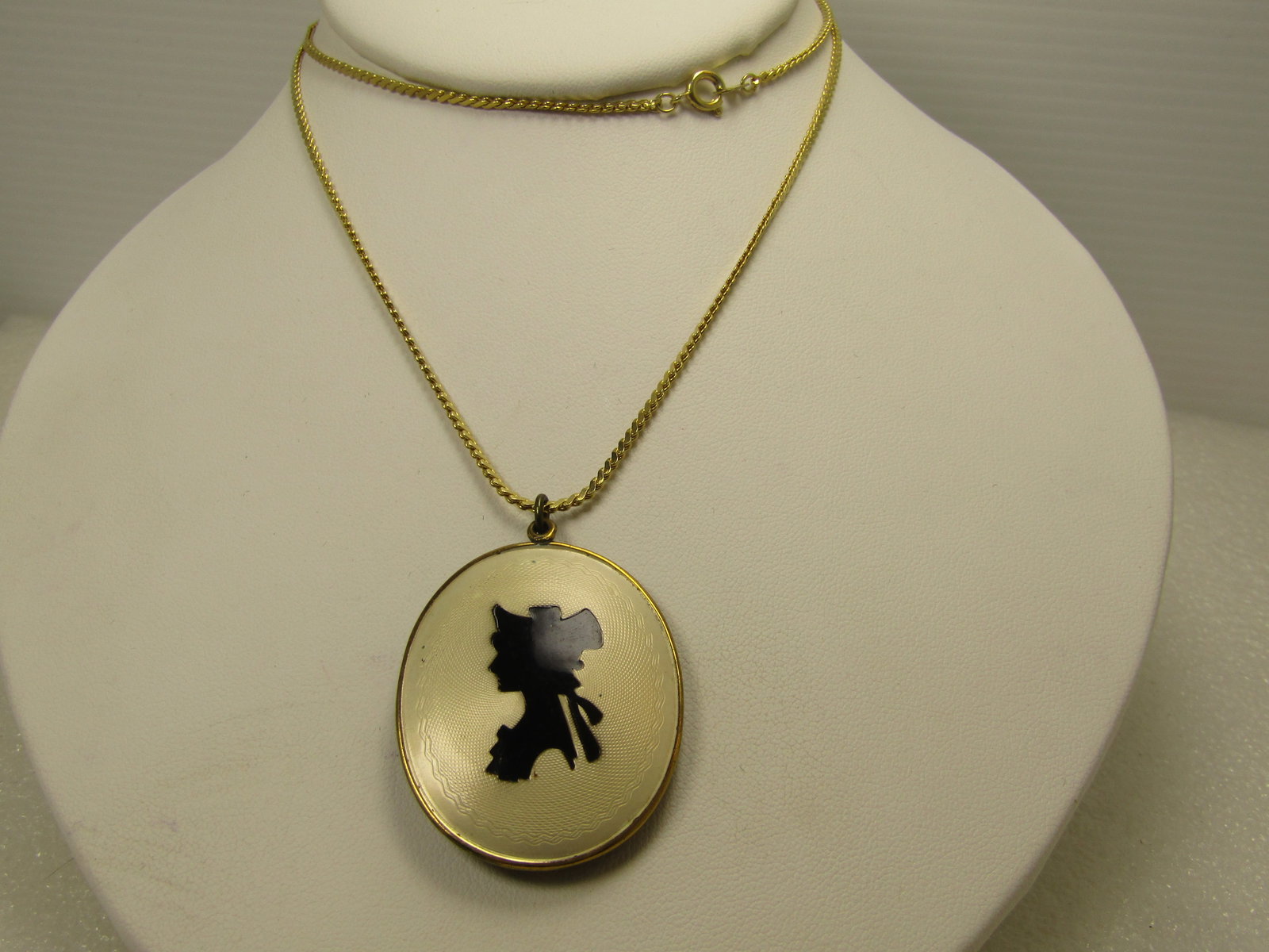 Vintage Black/White Shilouette Locket Necklace, 24", 1940's-1960's: Vintage Black/White Shilouette Locket Necklace, 24", 1940's-1960's. The top is slightly domed with a slightly off white background that has a cut finish - guilloche look - in an oval design and a rece