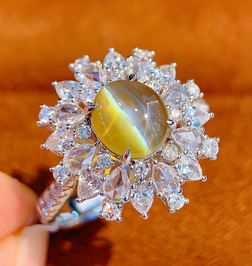 18K Gold Natural Chrysoberyl Cat's Eye Ring: Title: 18K Gold Natural Chrysoberyl Cat's Eye Ring Description: This ring features a natural chrysoberyl cat's eye as the centerpiece, showcasing a unique blend of rich gold and cool white hues. Its