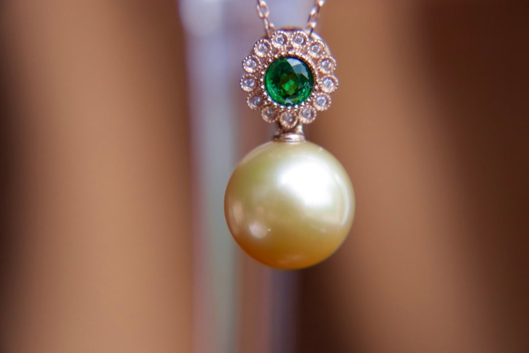 18K Gold Seawater Pearl Pendant: Title: 18K Gold Seawater Pearl Pendant Description: This 18K gold pendant features a 12.32mm seawater pearl, exhibiting a perfect round shape and strong luster. Flawless and complemented by natural Ts