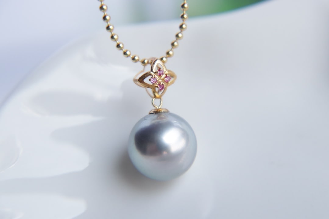 18K Gold Tahitian Pearl Pendant: Title: 18K Gold Tahitian Pearl Pendant Description: This 18K gold Tahitian pearl pendant is renowned for its perfectly round shape and intense luster. The pearl, with a diameter of 10.5mm, exhibits a