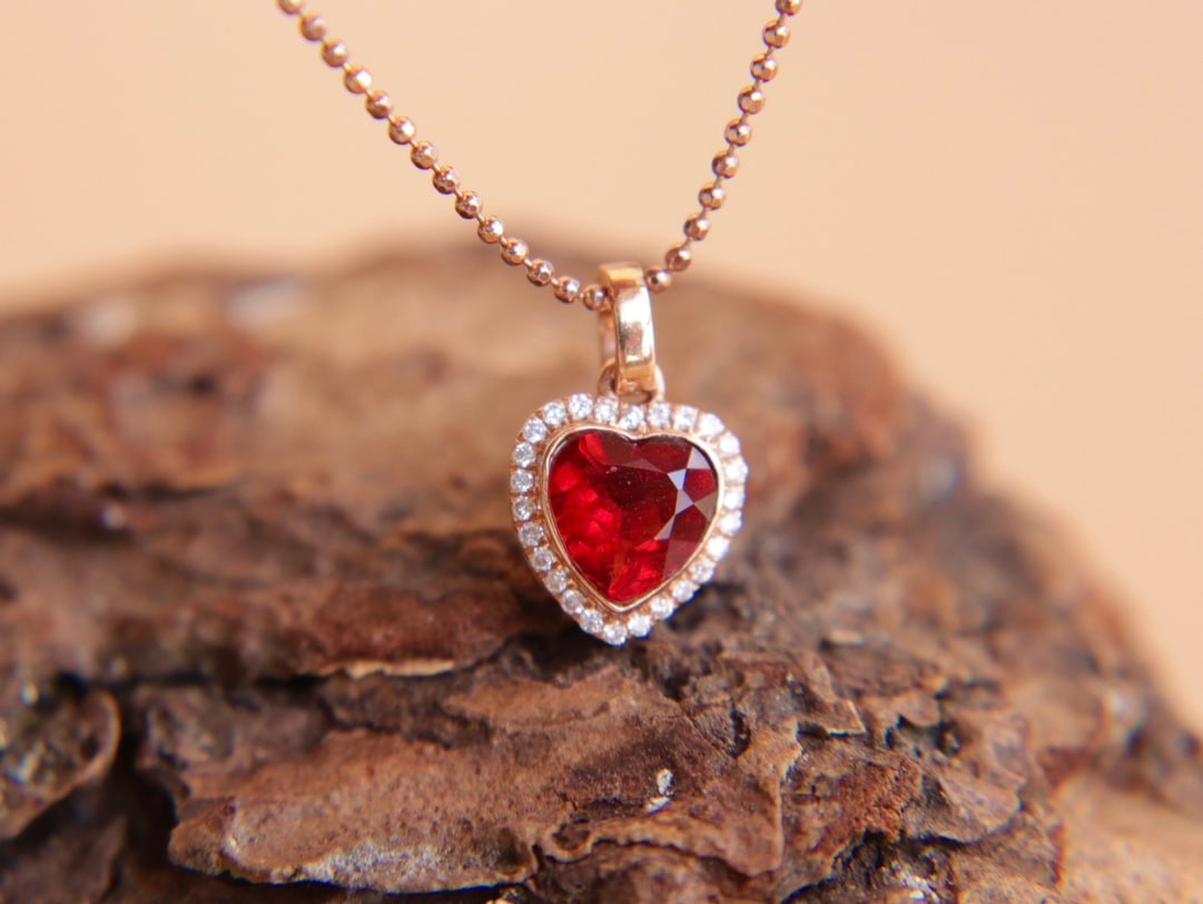 18K Gold Sunstone Diamond Pendant: Title: 18K Gold Sunstone Diamond Pendant Description: This pendant is meticulously set in 18K gold, featuring a ruby-colored sunstone as the main stone. It exudes a rich golden hue with a cool white