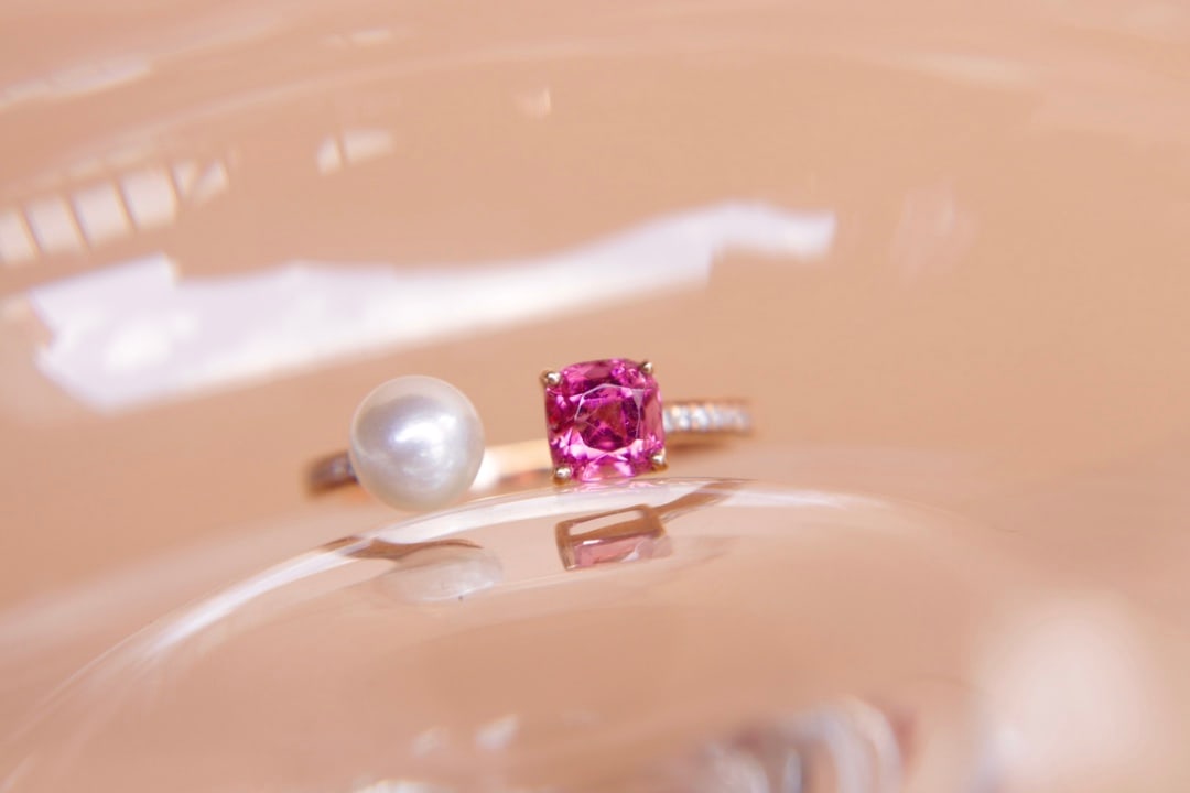 18K Gold Red Tourmaline Ring: Title: 18K Gold Red Tourmaline Ring Description: This 18K gold ring features a 0.685-carat rubellite as the center stone, paired with an Akoya saltwater pearl, showcasing its natural rich gold hue