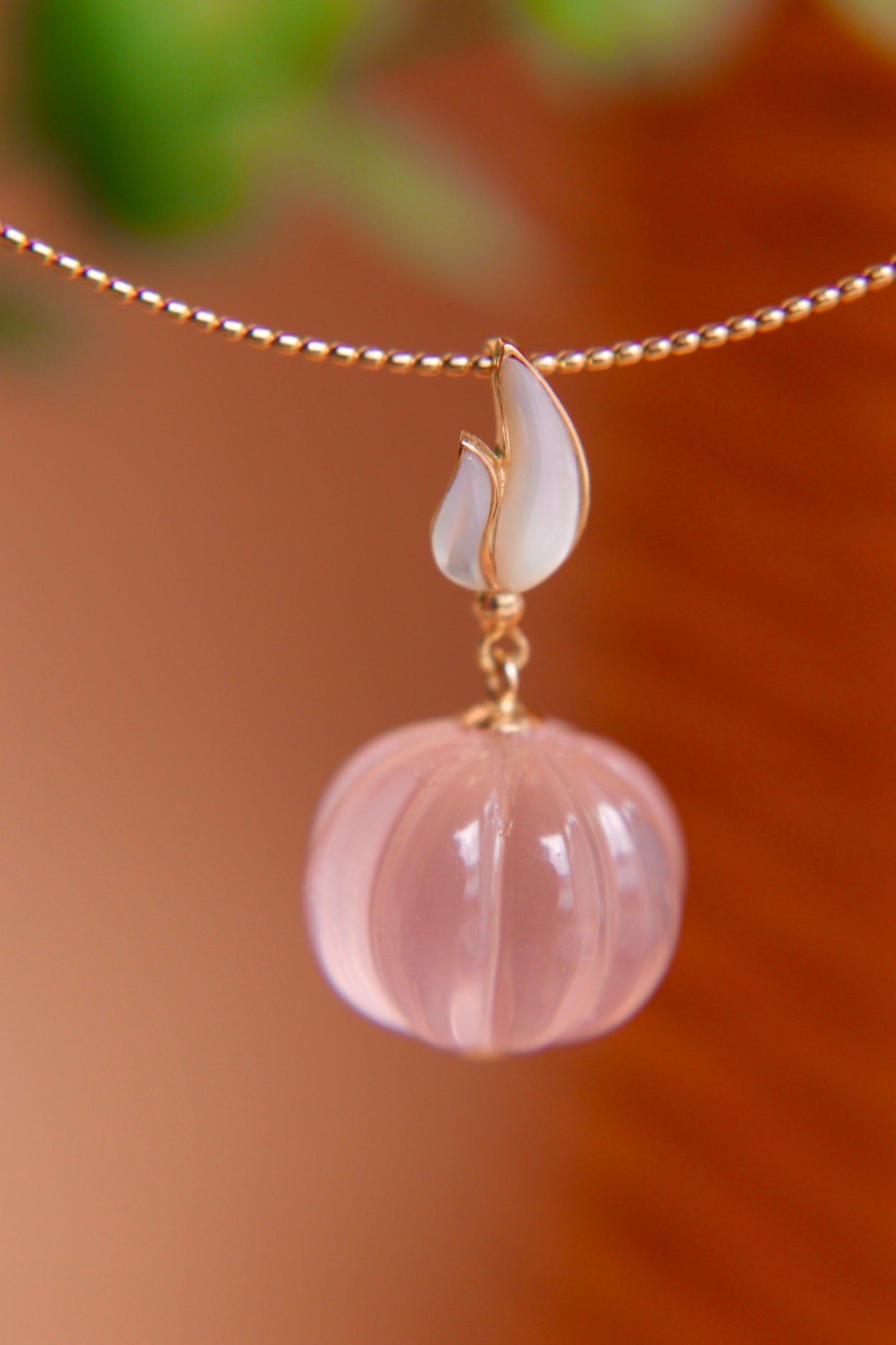 18K Gold Natural Pumpkin Rose Quartz Pendant: Title: 18K Gold Natural Pumpkin Rose Quartz Pendant Description: This pendant features a natural pumpkin rose quartz set in 18K gold, complemented by a cool white mother-of-pearl rose clasp. It