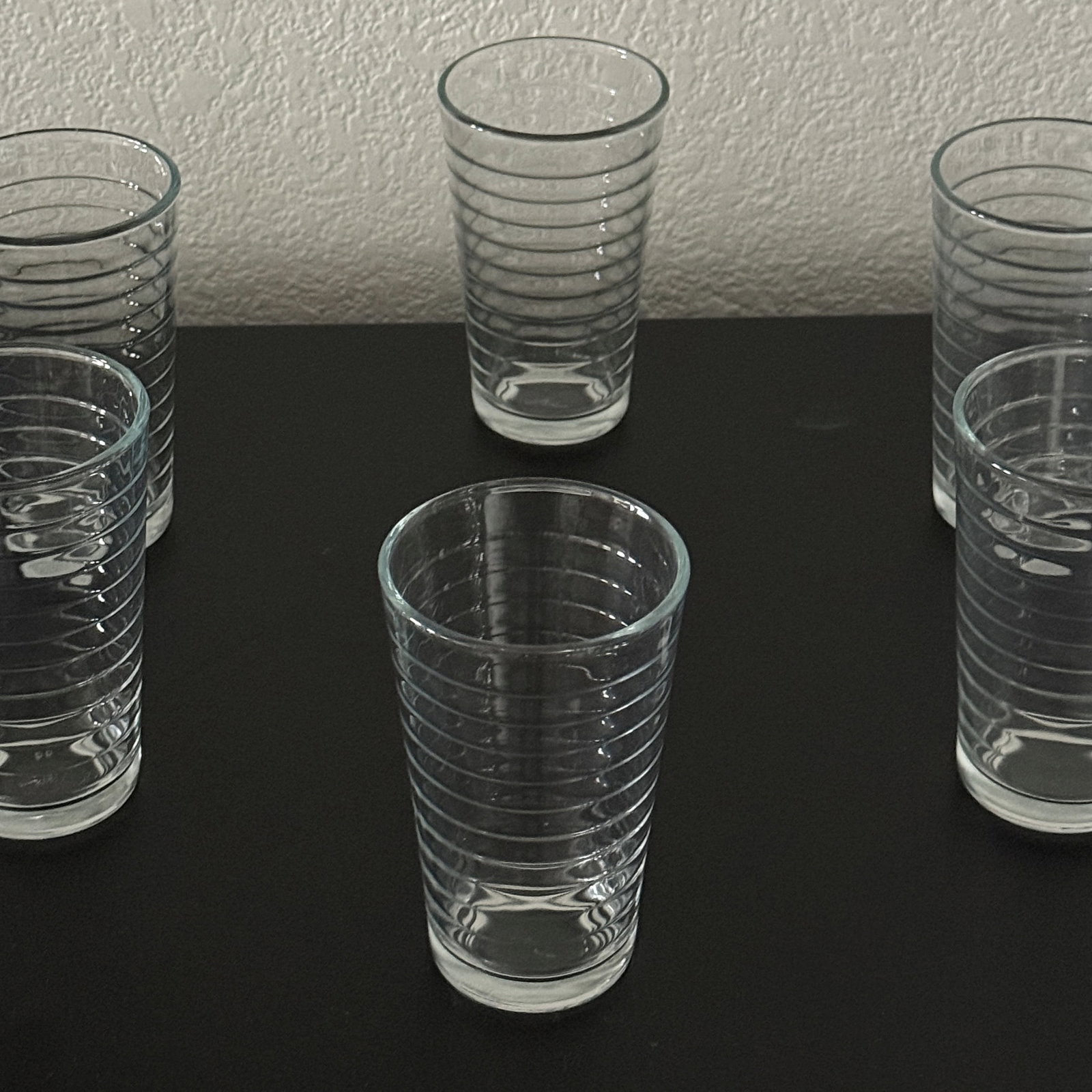 Set of Six Tall Ribbed Glass Tumblers: A contemporary set of six clear glass tumblers, each featuring a ribbed design for an enhanced grip and a touch of classic diner style. The glasses have a sturdy base and a smooth rim, suitable for ev