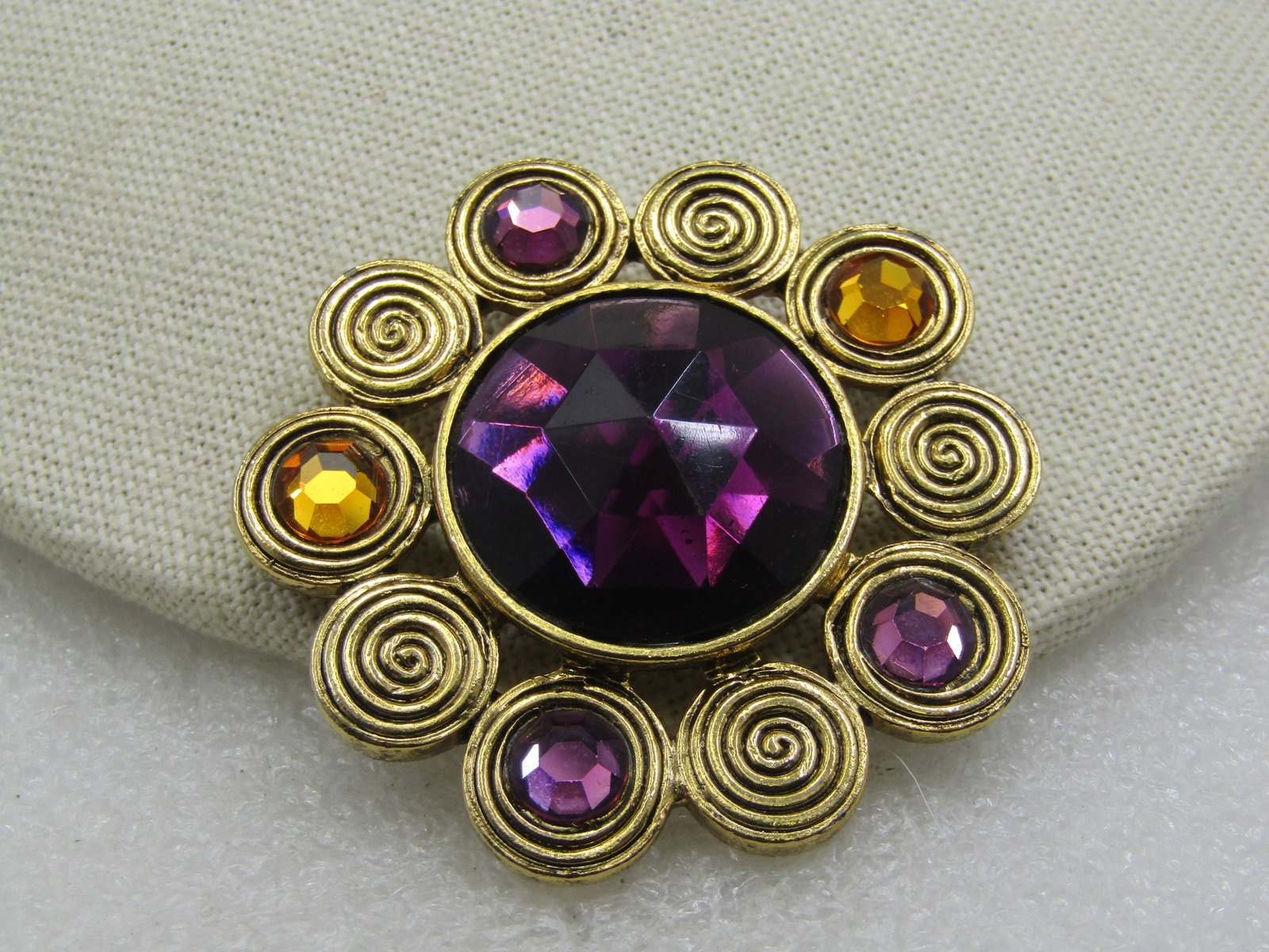 Enameled Silver Tone Bear Tack Pin, Blue & Red, Black Eyes: Vintage Craft Signed Brooch, Purple & Yellow Rhinestones, 2". Gold tone with a center faceted 25mm acrylic rhinestone and around that are spiral circles framing the mani stone with three of them