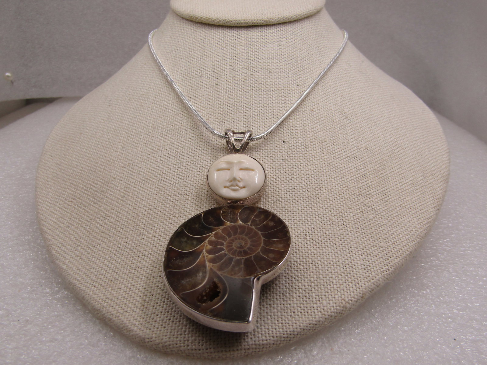Vintage Sterling Ammonite & Moon Face Pendant on 20" Plated Chain: Vintage Sterling Ammonite & Moon Face Pendant on 20" Plated Chain. The pendant is marked .925 and tested. It is appx. 3" by 1.5" and weight is appx. 27.30 gr. for pendant only. It has a bezel-framed a