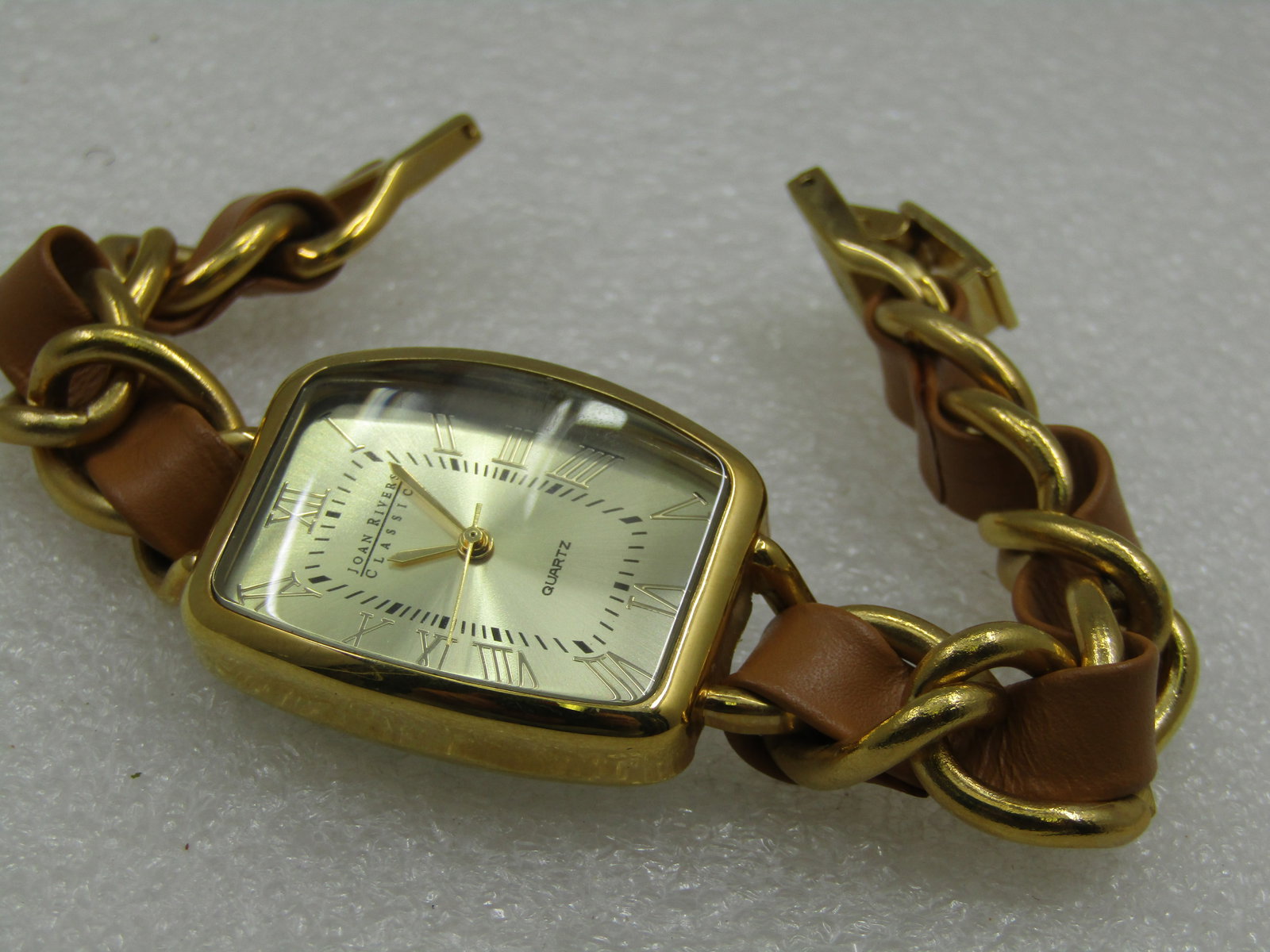 Vintage Joan Rivers Gold Tone Quartz Watch, Leather Weave, 7": Vintage Joan Rivers Gold Tone Quartz Watch, Leather Weave, 7". The watch is 31.5mm long and 25mm at center where the stem is and 21mm at the top and botom edge. Roman numbers. Joan Rivers Classics, Se