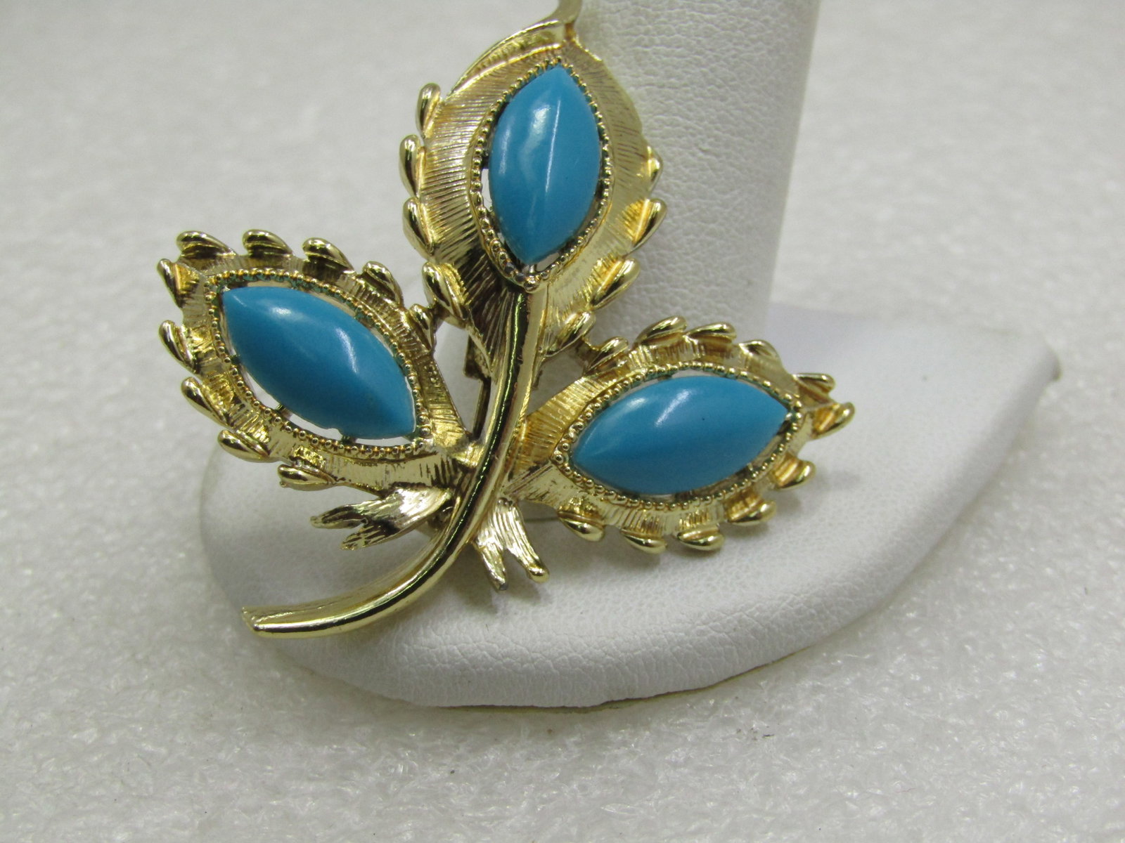 Vintage Faux Turquoise Leaf Stem Brooch, 1960's-1970's: Vintage Faux Turquoise Leaf Stem Brooch, 1960's-1970's, Gold tone textured finish. 2" by 1.75". The faux turquoise are marquise shaped, domed and appx. 15mm by 6mm. Very good condition. Not signed by 