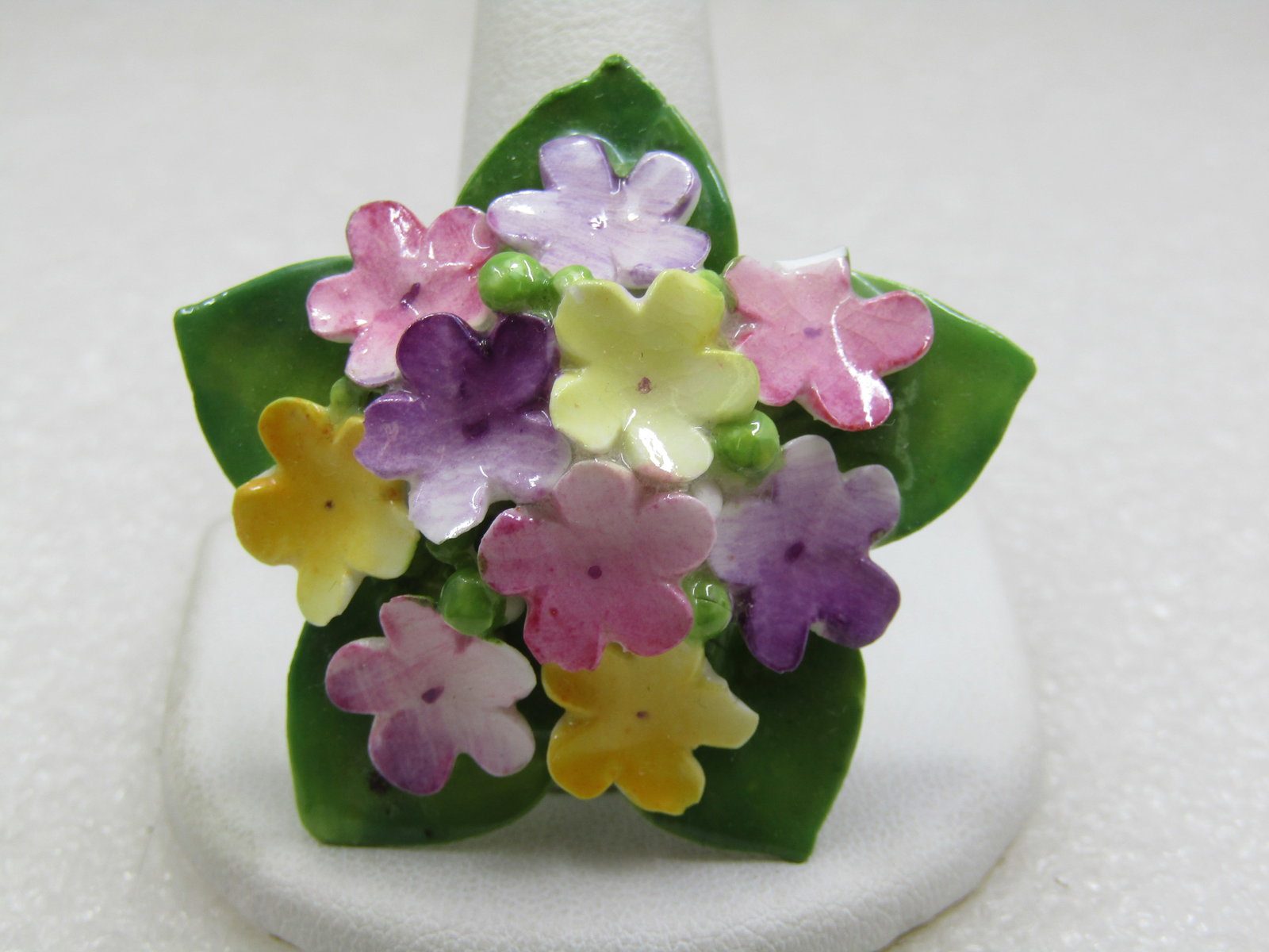 Vintage Porcelain Forget-me-Not Brooch, Cara China, Staffordshire, England: Vintage Porcelain Forget-me-Not Brooch, Cara China, Staffordshire, England, It has a base of pointed green elaves and a mount of pink, purple, lavender forget-me-not blossoms. The one pink blossom