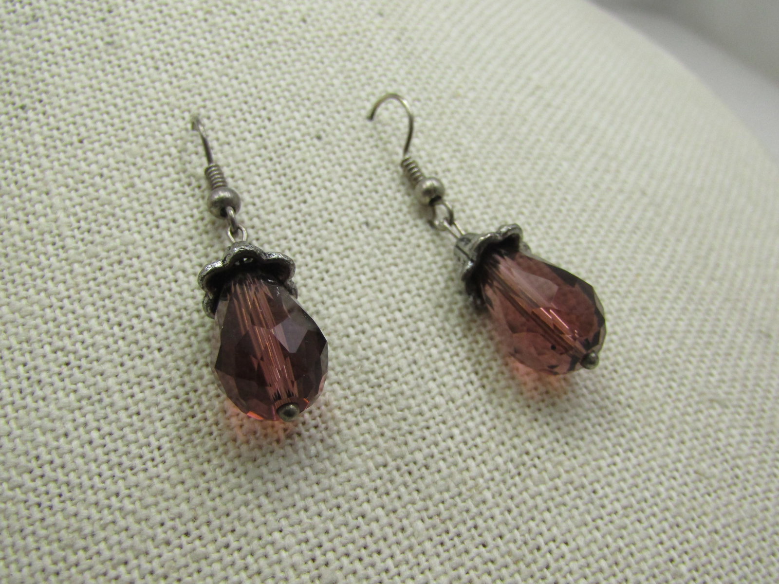 Vintage Amethyst Glass Briolette Drop Earrings, 1.5": Vintage Amethyst Glass Briolette Drop Earrings, 1.5". Pierced earrings measured frm the curve in the surgical steel post. Decorative faux marcasite top cap. Age is 1980's or after. Very good