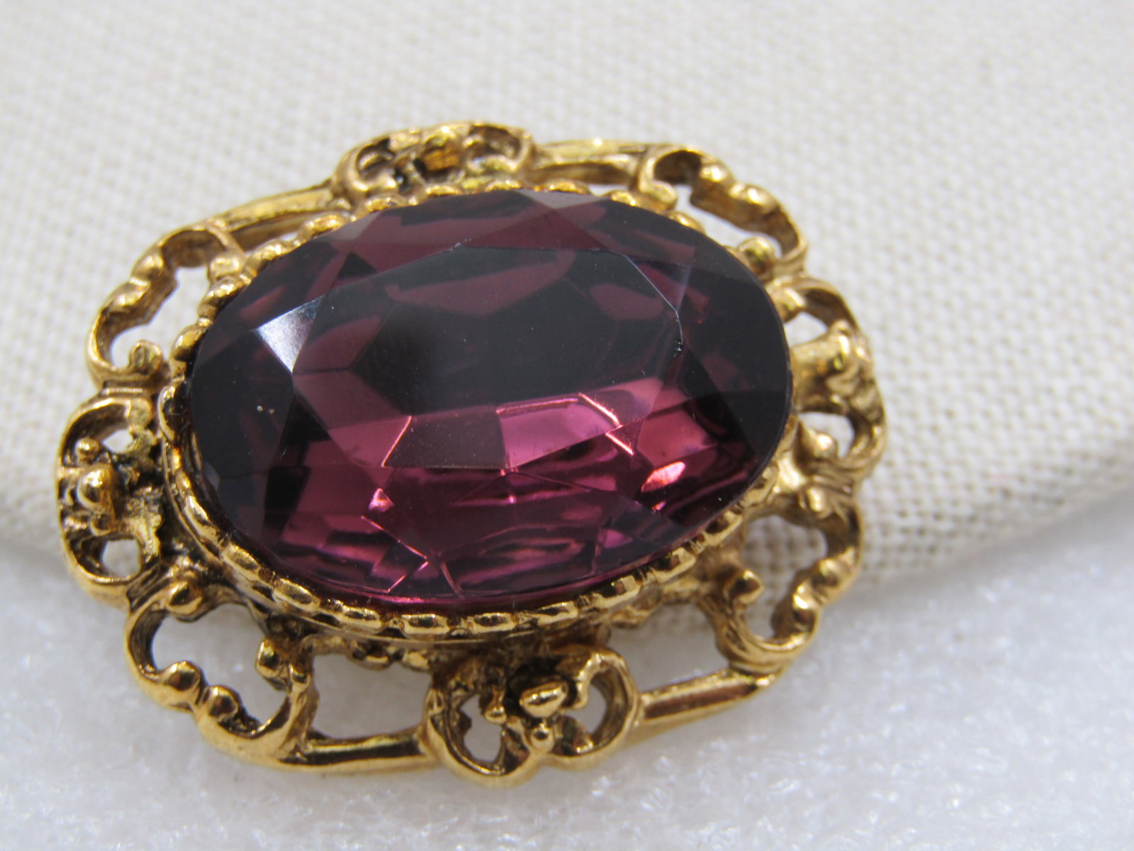 Vintage Victorian Themed Purple Rhinestone Brooch, 1.5": Vintage Victorian Themed Purple Rhinestone Brooch, 1.5" by 1.25". Gold tone bezel-set 25mm by 19mm purple faceted glass stone with an open scrolled frame. Not signed by the maker. Age is appx.