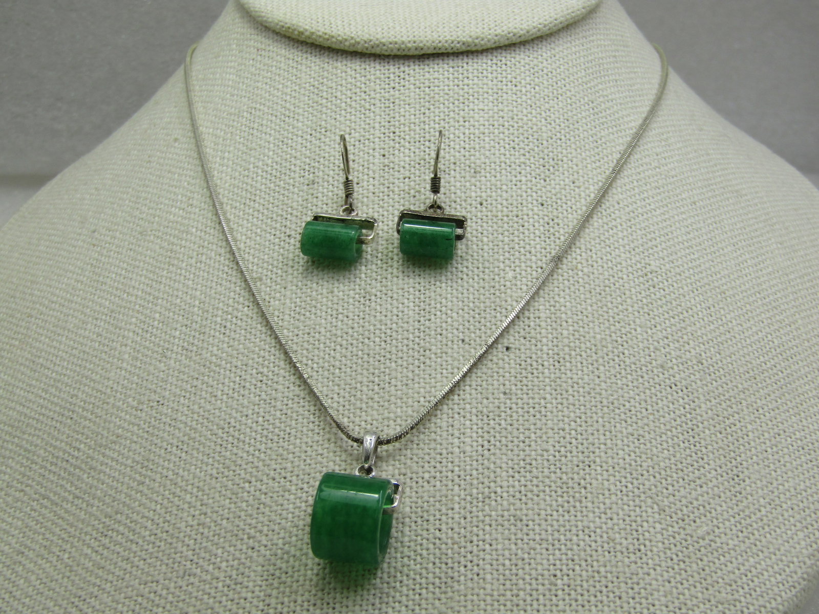 Silver Plated Jadeite Necklace & Pierced Earring, 19" Square Serpentine Chain: Silver Plated Jadeite Necklace & Pierced Earring, 19" Square Serpentine Chain. The pendant and earrings have a tubular green stone that does test as Jadeite. Very green. The pendant is 12mm round and