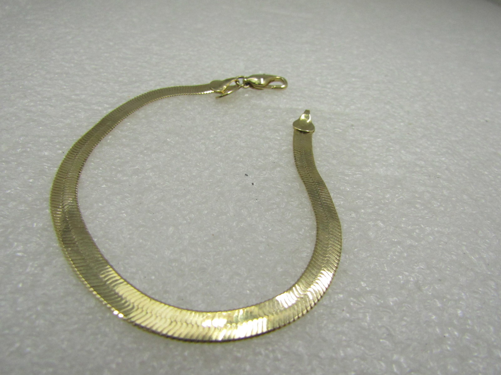 Vintage Gold Tone Herringbone Bracelet, 7.5", 4.5mm, American Showcase: Vintage Gold Tone Herringbone Bracelet, 7.5", 4.5mm, American Showcase. Bright gold tone finish with lobster clasp and American Showcase hang tag, Made in Korea. 1980's-1990's. Very good condition.