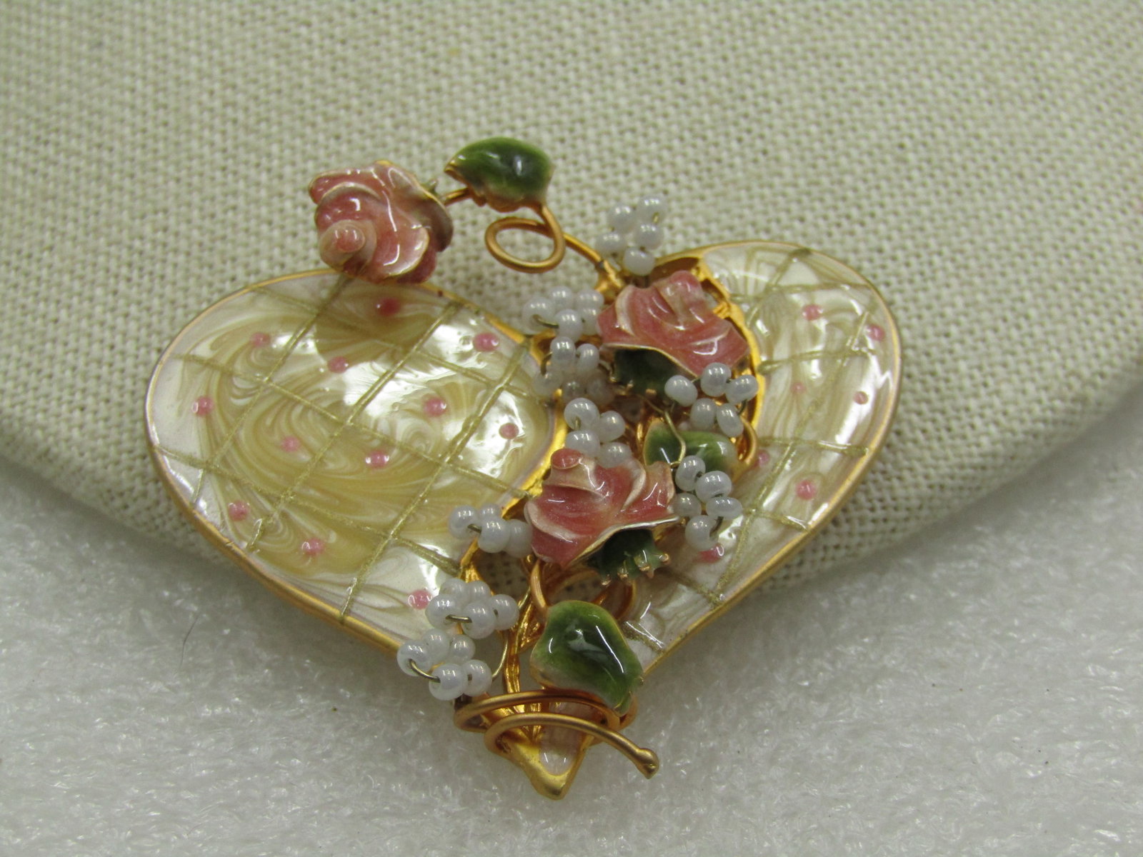 Vintage Enameled Heart Brooch with Trailing Roses & Faux Pearls: Vintage Enameled Heart Brooch with Trailing Roses & Faux Pearls. It has a coil over the heart that is a pearly tan enameleding with a gold tone grid and pin dot accents. The coil is a coppery rose