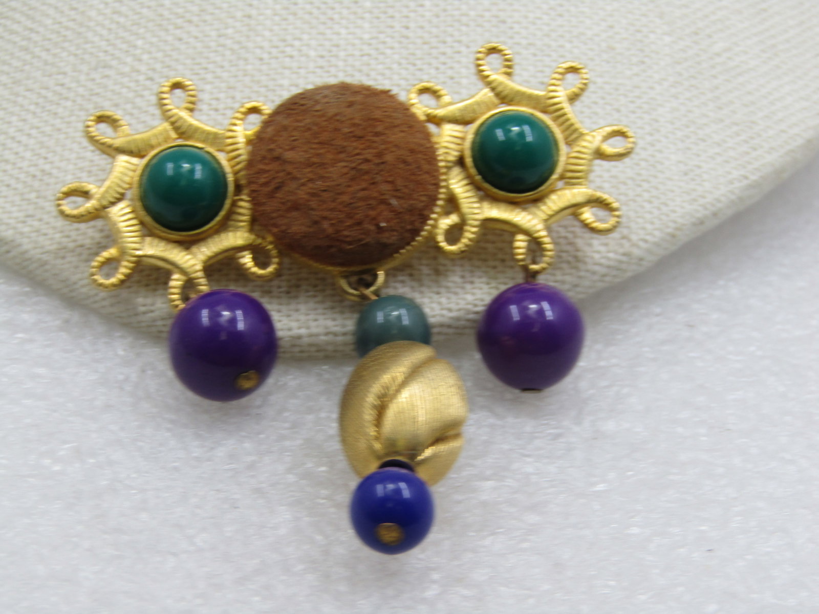 Vintage Bar Brooch with Dangle Beads & Suede Accent, 1980's-1990's: Vintage Bar Brooch with Dangle Beads & Suede Accent, 1980's-1990's. Gold tone with a looped circle on each side of a center brown suede button. Thre is a green 8.5mm round cabochon in each of the