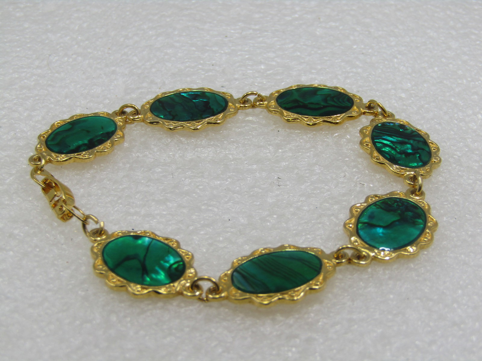 Vintage Green Simulared Paua Shell Bracelet, 8", 1960's-1970's: Vintage Green Simulared Paua Shell Bracelet, 8", 1960's-1970's. It has scrolled edges with a stamped design on the seven oval links with a green created or simulated paua shell that is appx. 14mm by 1