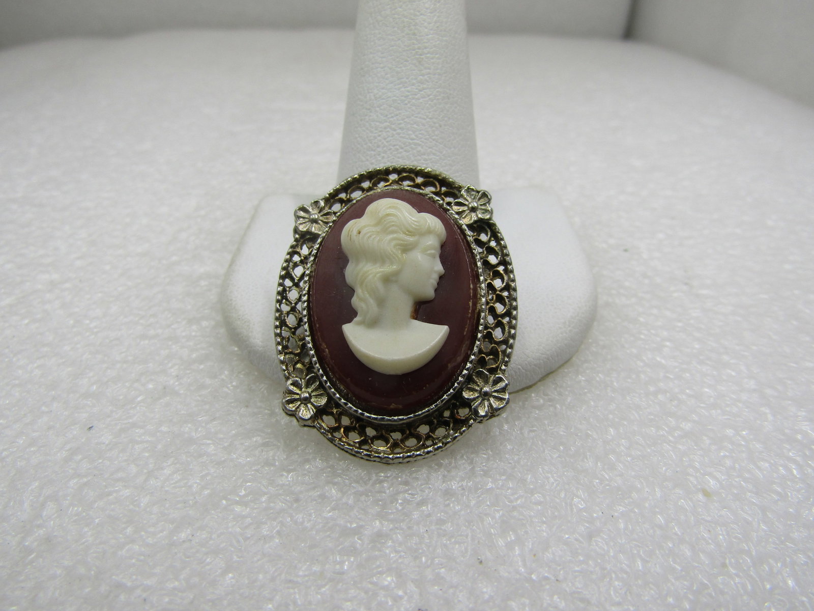 Vintage Cameo Brooch, 1950's-1960's, 1.5": Vintage Cameo Brooch, 1950's-1960's, 1.5", Gold tone and Silver tone filigree frame with floral accents. Molded white plastic cameo on a faux carnelian hued background. It is 1.5" tall and 1" wide.