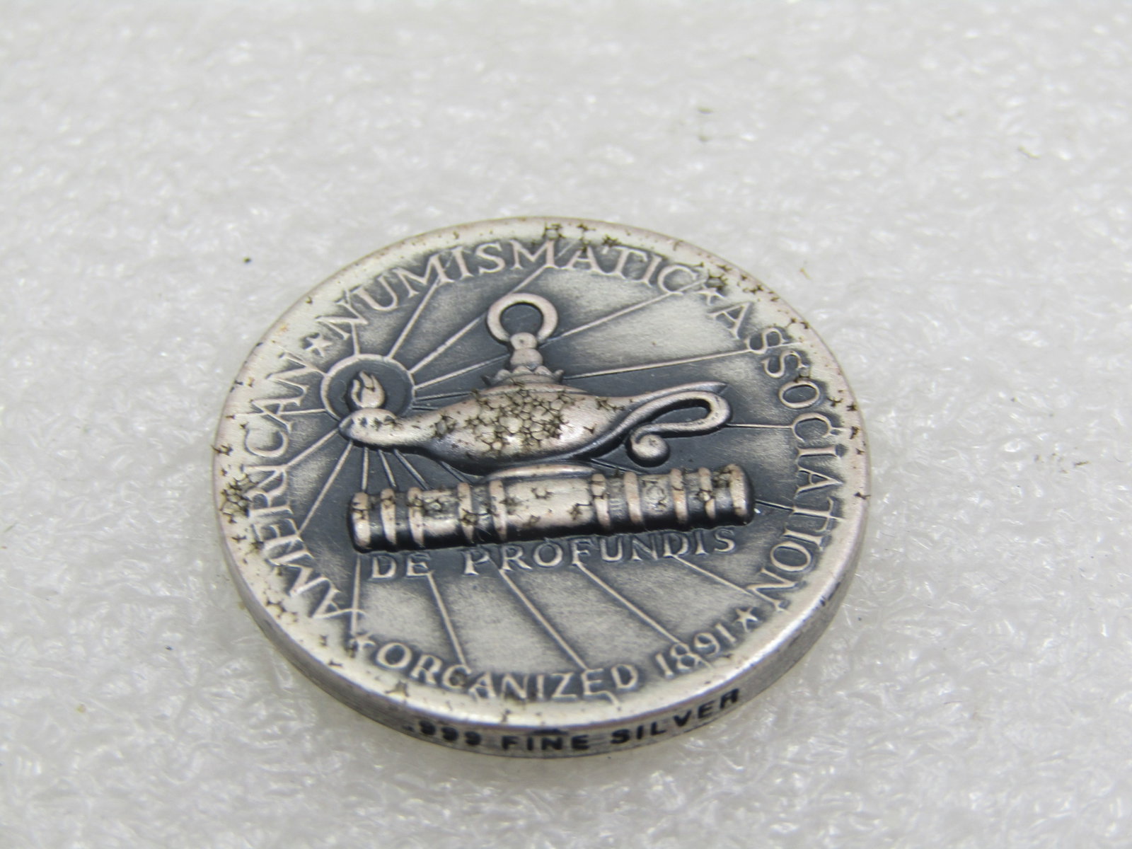 .999 Silver 25 Year Membership American Numismadic Association Coin, 1999: 999 Silver 25 Year Membership American Numismadic Association Coin, 1999. Dated with K82466 number on coin. Stamped .999 find silver on side edge of coin. In original foam-lined boxed it was