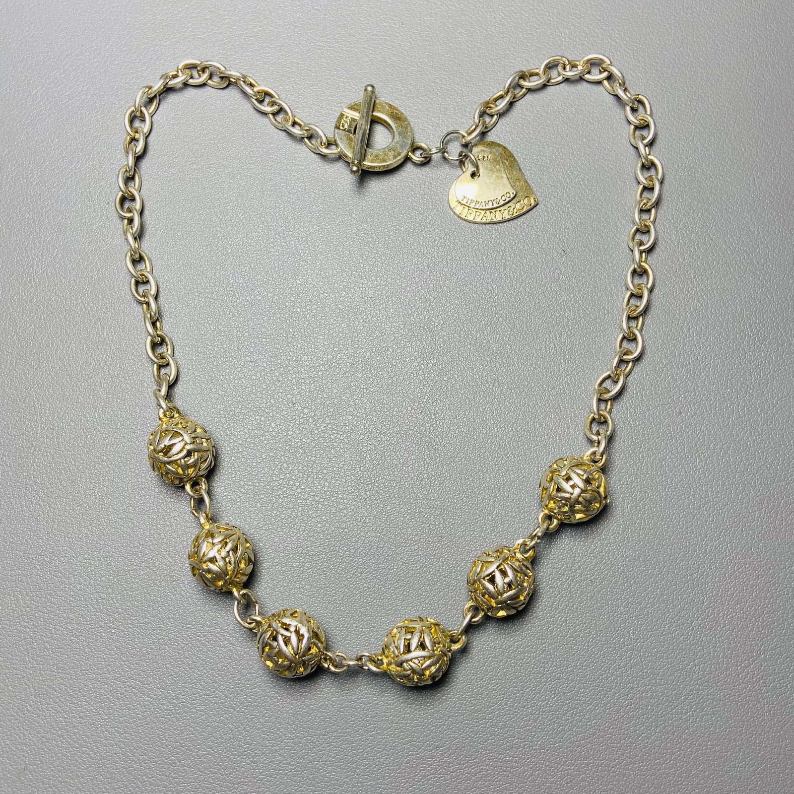 Vintage Tiffany & Co. Double Heart Tag Toggle 925 Sterling Silver Choker Necklace: Title: Vintage Tiffany & Co. Double Heart Tag Toggle 925 Sterling Silver Choker Necklace Description:The centerpiece of the necklace features a gracefully intertwined double heart tag that serves as