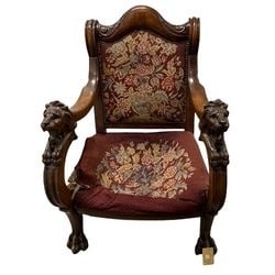 Victorian Carved Mahogany Armchair with Lion Heads and Needlepoint Upholstery: This Victorian-era armchair features a richly carved mahogany frame, distinguished by prominent lion's head armrests with intricate detailing. The arms terminate in paw feet, complementing the overall