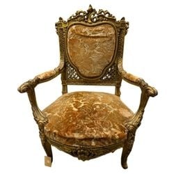 Giltwood and Upholstered Armchair in Louis XV Style: An ornate armchair crafted in the Louis XV style, featuring a heavily carved giltwood frame with rocaille motifs, C-scrolls, and floral accents. The chair is upholstered in a rich, patinated gold and 
