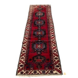 Hand-Knotted Baluchi Tribal Runner Rug: A finely hand-knotted Baluchi tribal runner rug, likely from the mid to late 20th century. This rug features a rich, deep red field adorned with five prominent octagonal medallions in alternating