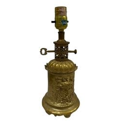 Gilt Metal Neoclassical Style Table Lamp: A gilt metal table lamp in the Neoclassical style featuring a cylindrical body adorned with ornate relief decorations, including a central Medusa-like face surrounded by foliage and classical motifs.