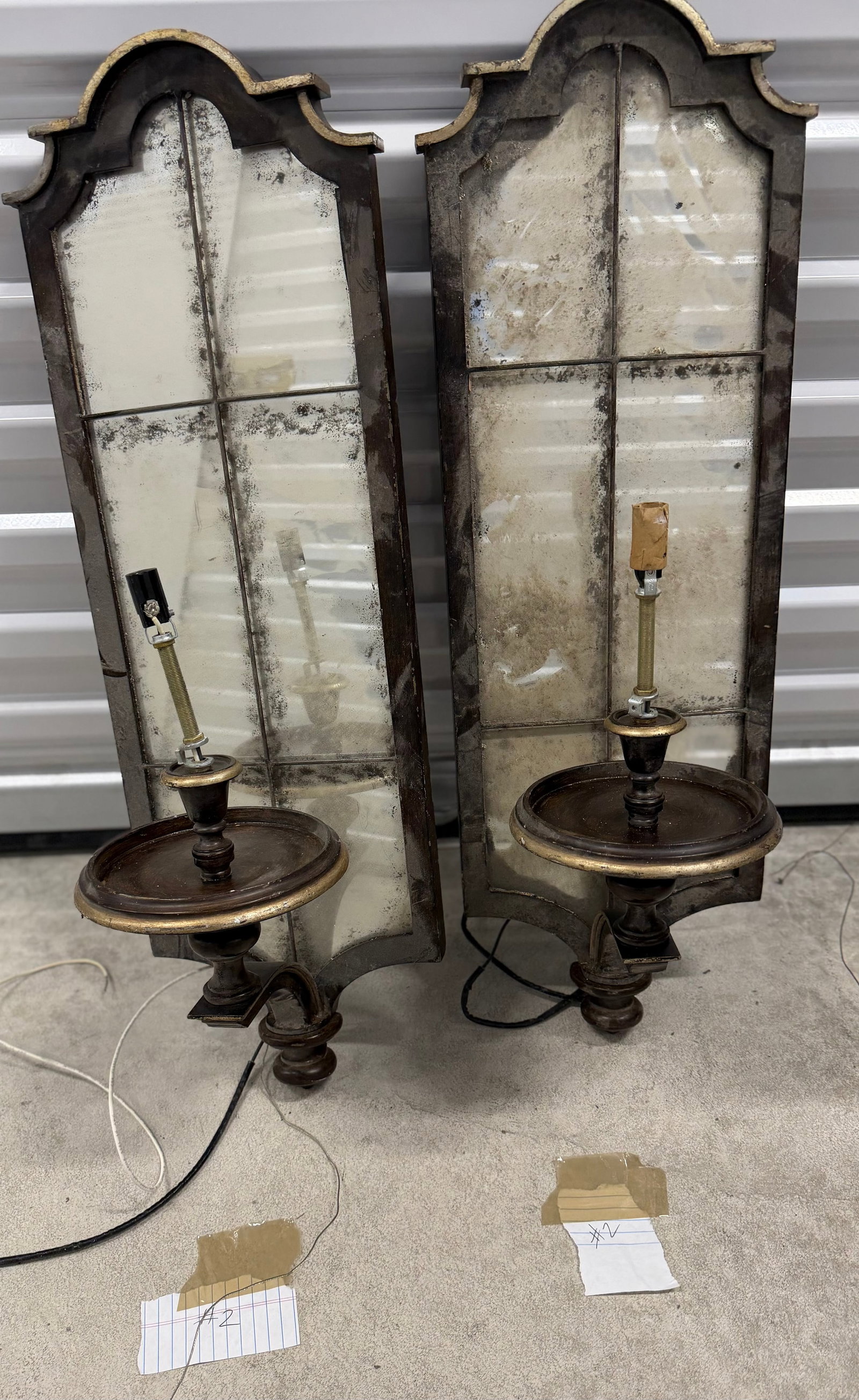 Pair of Ornate Giltwood and Mirrored Sconces #2: A pair of decorative sconces featuring an ornate giltwood frame with a distressed finish, enclosing a mirrored backplate divided into several panes. The sconces are designed to hold a single light