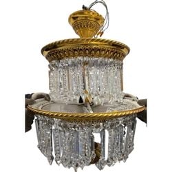 Gilded Brass and Crystal Two-Tier Chandelier: An ornate two-tier chandelier, likely from the Mid-Century Modern period, featuring a gilded brass frame adorned with multiple strands of rectangular and pointed crystal prisms. The crystals are