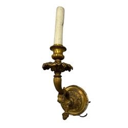 Gilt Bronze Wall Sconce, Neoclassical Style: A gilt bronze wall sconce in the Neoclassical style. The sconce features a fluted column leading to a decorative bobeche with floral and foliate motifs, supporting a single candle holder. The wall