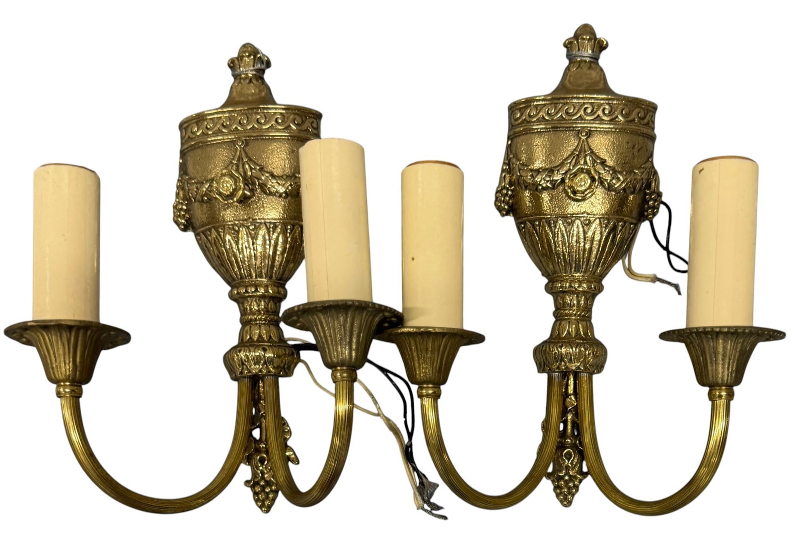 Pair of Neoclassical Style Gilt Bronze Two-Arm Sconces: A pair of Neoclassical style gilt bronze two-arm sconces, likely early 20th century. Each sconce features an urn-form backplate adorned with ornate cast decoration including laurel wreaths, ribbons, a