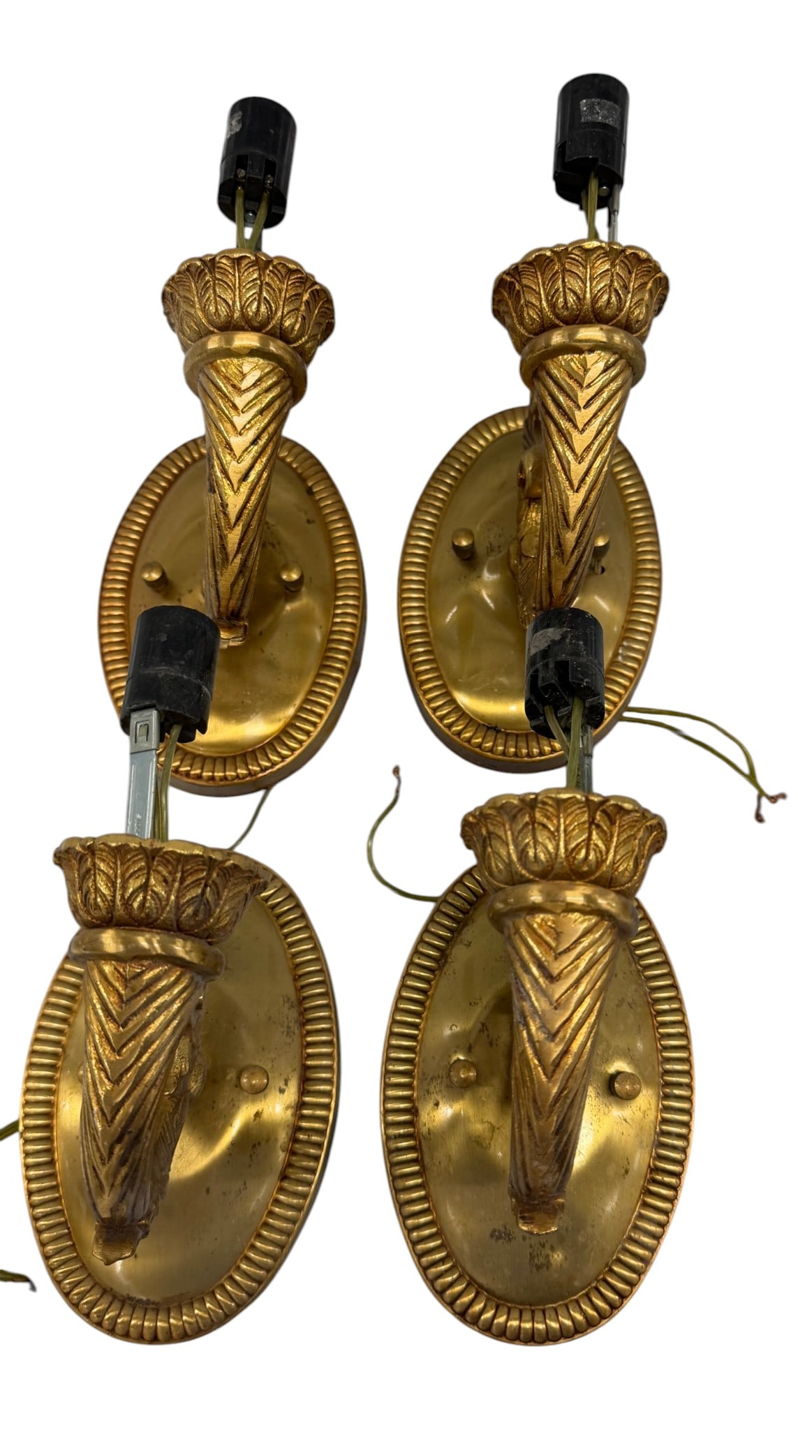 Set of Four Gilt Bronze Torch-Form Sconces: This is a set of four gilt bronze torch-form wall sconces, likely dating to the mid-20th century. Each sconce features an oval backplate with a fluted border, from which emerges a decorative torch-for