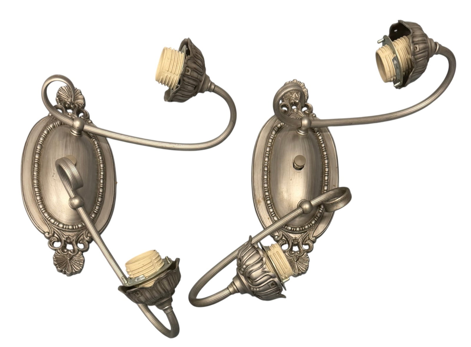 Pair of Rococo Revival Style Sconce Mounts (Two Pairs, Four Sconces Total): This lot features four sconce mounts in the Rococo Revival style, likely constructed from cast metal with a brushed silver-tone finish. Each mount features an oval backplate adorned with foliate and
